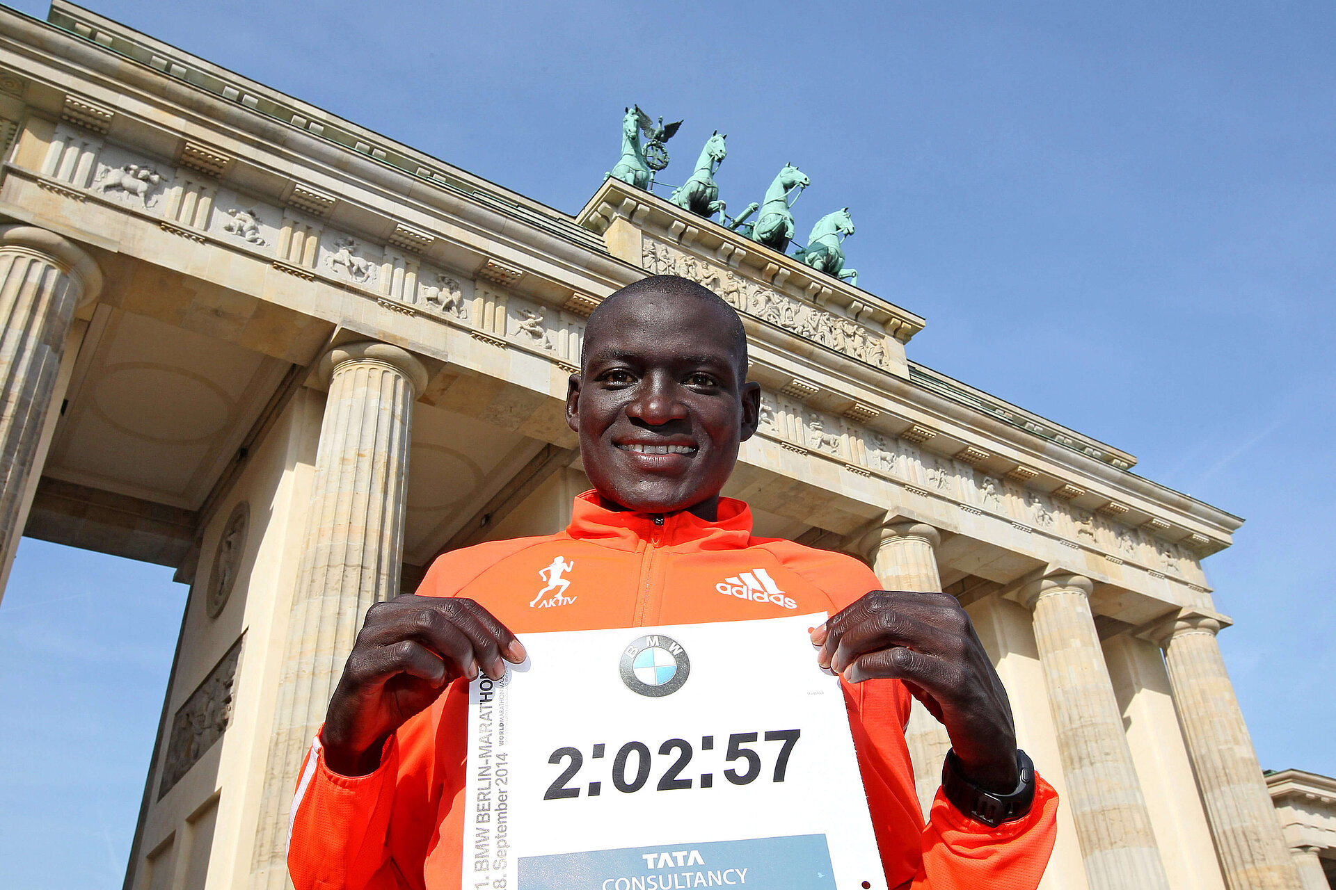 BMW BERLIN-MARATHON 2014: Winner Dennis Kimetto proudly shows his world record time to the camera in front of the Brandenburg Gate © SCC EVENTS