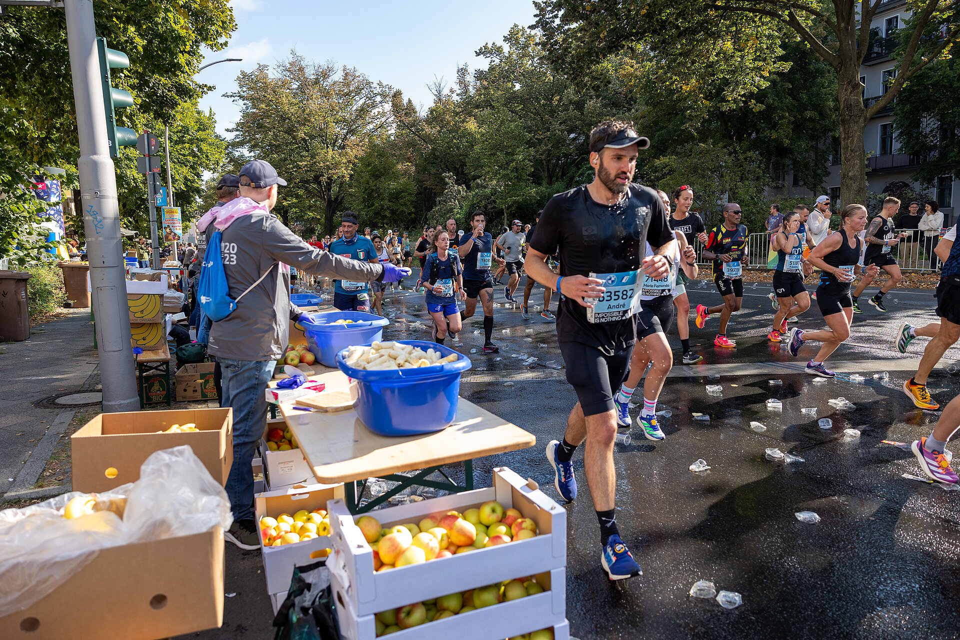 BMW BERLIN-MARATHON 2023: Läufer:innen erhalten an der Verpflegungsstation Obst © SCC EVENTS / Norbert Wilhelmi