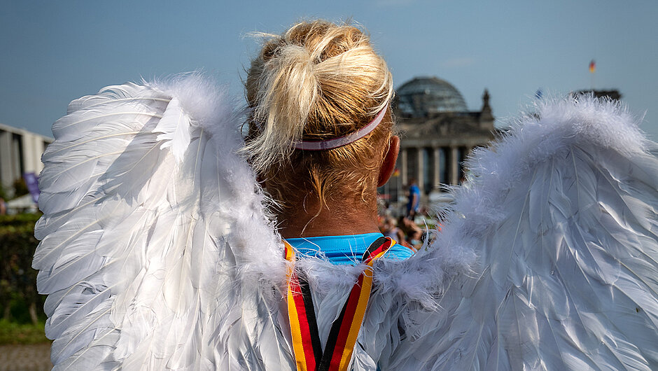 BMW BERLIN-MARATHON: Läufer:in mit Engelsflügeln schaut auf den Berliner Reichstag © SCC EVENTS/camera4