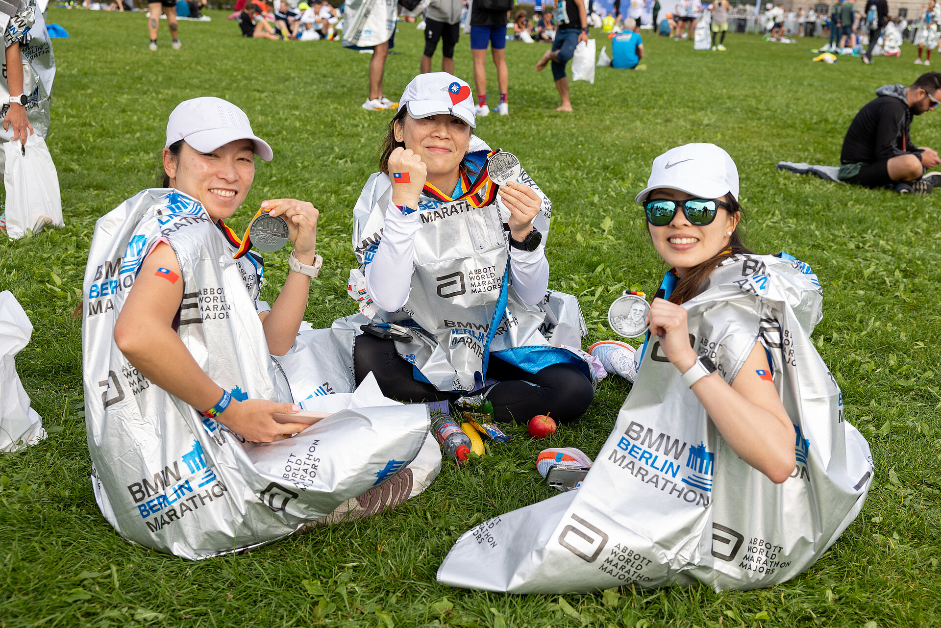 BMW BERLIN-MARATHON: Frauen im Poncho auf einer Wiese © SCC EVENTS / Nobert Wilhelmi