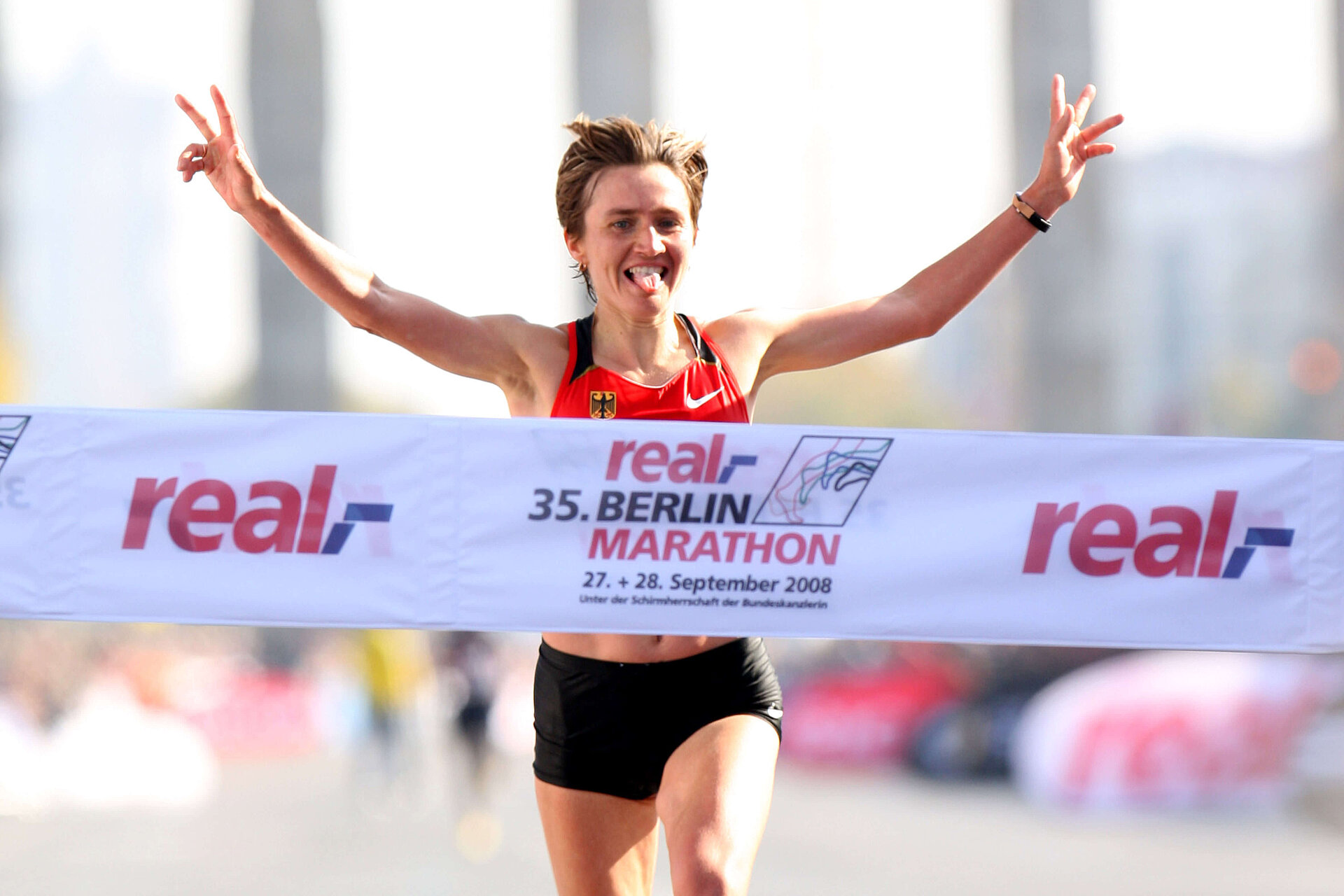 BMW BERLIN-MARATHON 2008: Irina Mikitenko raises her arms at the finish line and shows the victory sign © SCC EVENTS